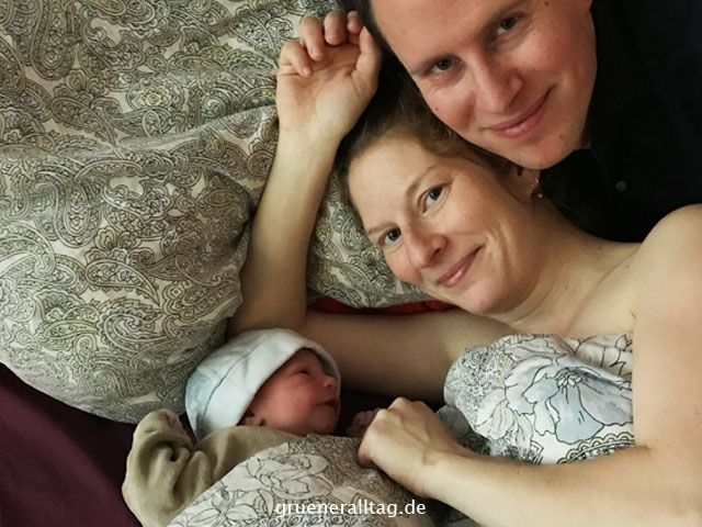 neugeborenes Hypnobirthing Baby lacht Mama und Papa an